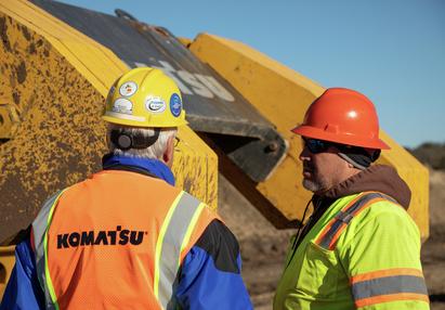 Two technicians standing in front of Komatsu D155CX pipe layer