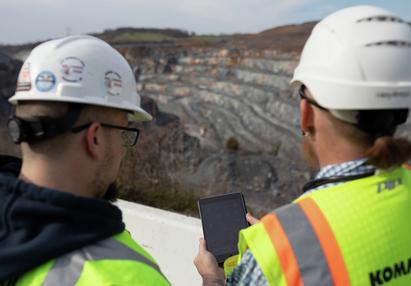 Two technicians looking at tablet in front of quarry