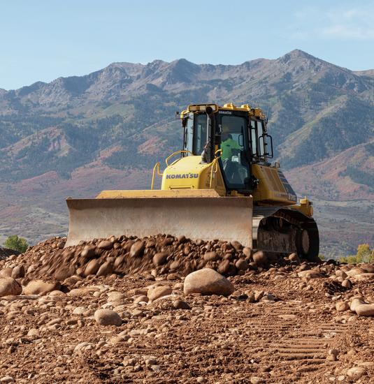 Komatsu D61PXi-24 dozer pushing material on job site with mountains in the background