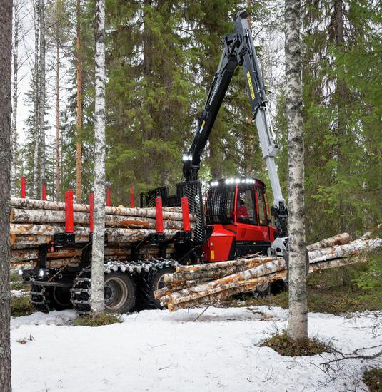 Komatsu 845 forwarder lifting several logs in snowy forest