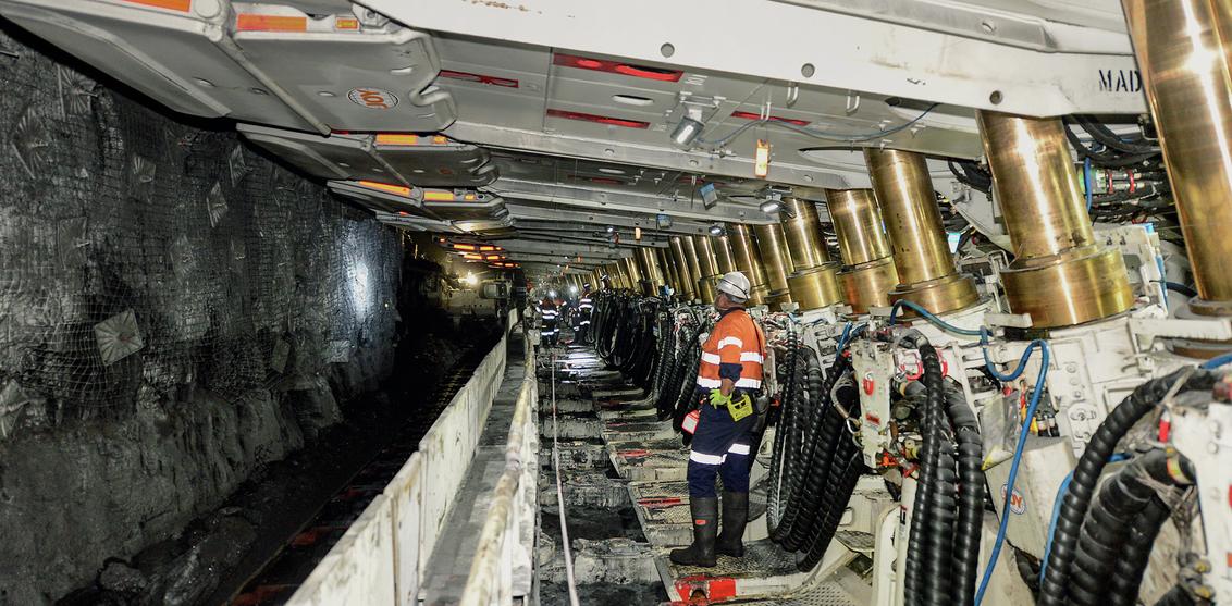 Worker with white longwall machine in underground mine
