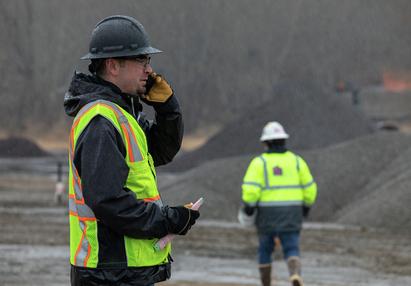 Worker on phone in construction site with worker in background