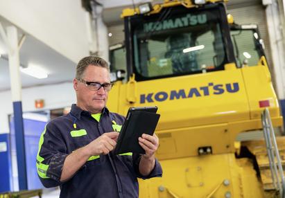Technician working on tablet in front of Komatsu dozer