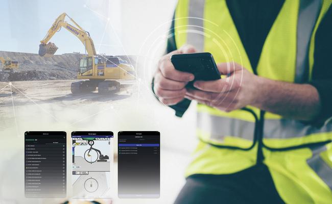 Man using Smart Construction Remote on phone with excavator in the background